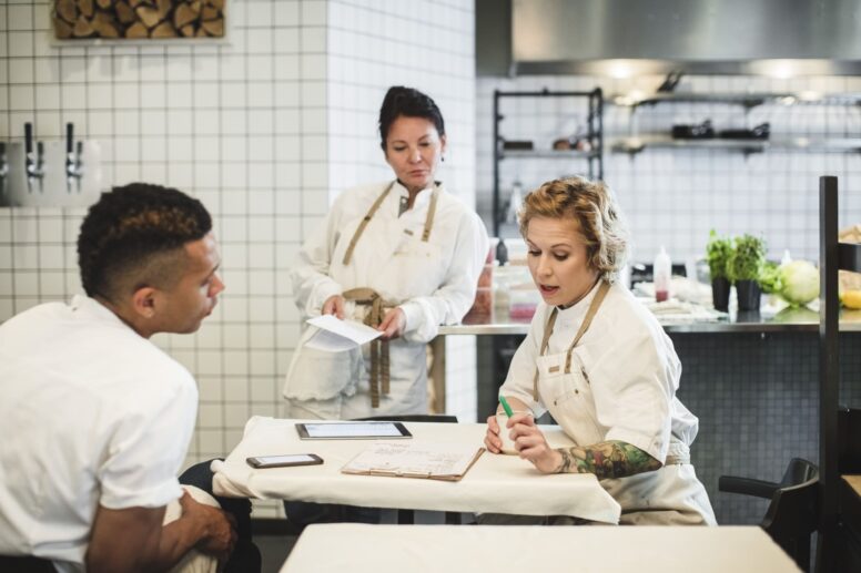 Drei Gastronomen sitzen zum Planen in der Küche zusammen