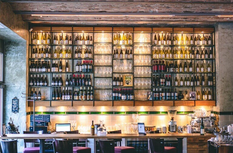 Un bar à vin avec de nombreuses bouteilles de vin différentes sur une étagère