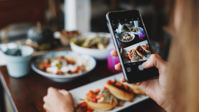 Person macht mit dem Handy ein Bild vom Essen im Restaurant