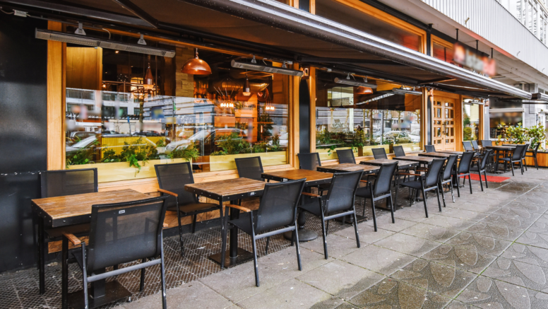 Restaurant Außenansicht mit Tischen und Stühlen vor einer großen Glasfront